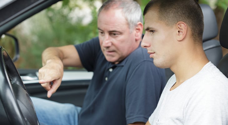 Parent lecturing teenage son driving a car