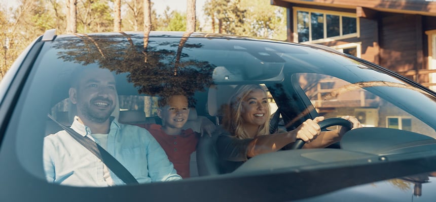 Smiling family driving car through the woods