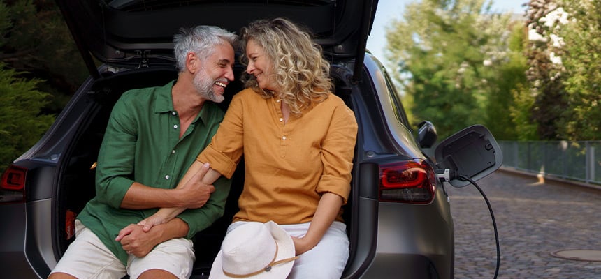 Older couple smiling while seated in the trunk of the car