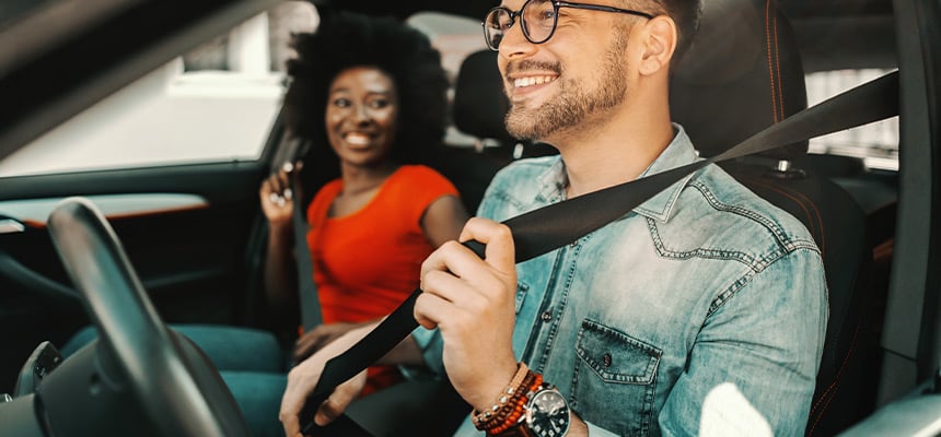 Young couple smiling and putting on seatbelts
